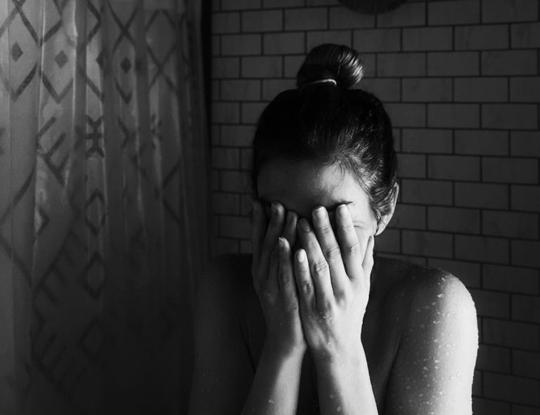 grayscale photo of woman covering her face with her hands