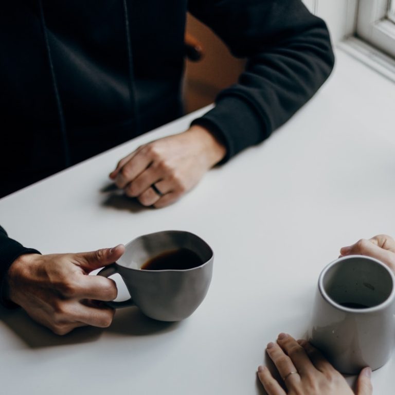 a couple of people sitting at a table with cups of coffee