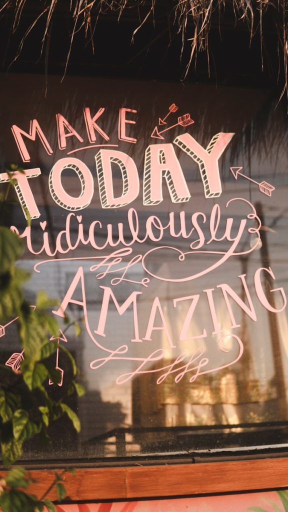 The image shows a motivational quote on a window: "Make Today Ridiculously Amazing," surrounded by decorative elements.