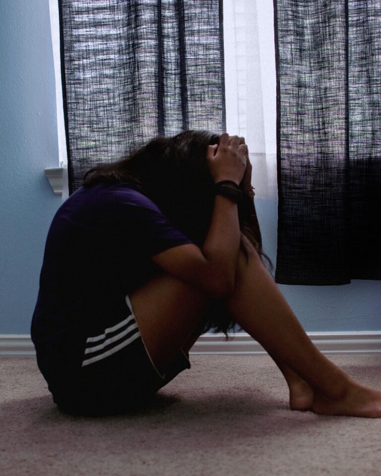 a woman sitting on the floor depressed with her head in her hands